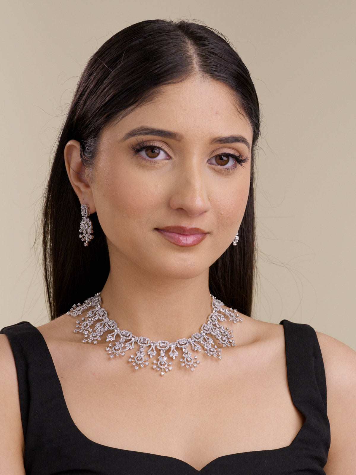 Model wearing a silver tone American Diamond necklace set with clear stones, matching earrings, square stone links, and floral-inspired drop detailing.