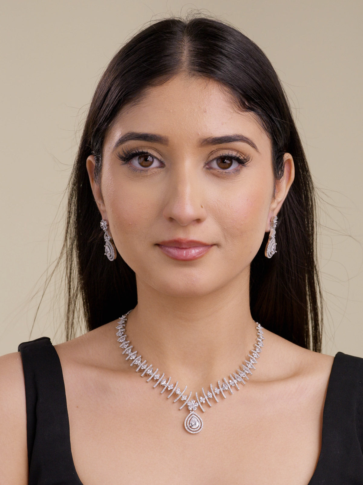 Model wearing a silver tone American Diamond necklace set with CZ stone bar detailing, matching teardrop earrings, floral cluster accents, and a centre teardrop pendant in a front portrait shot.