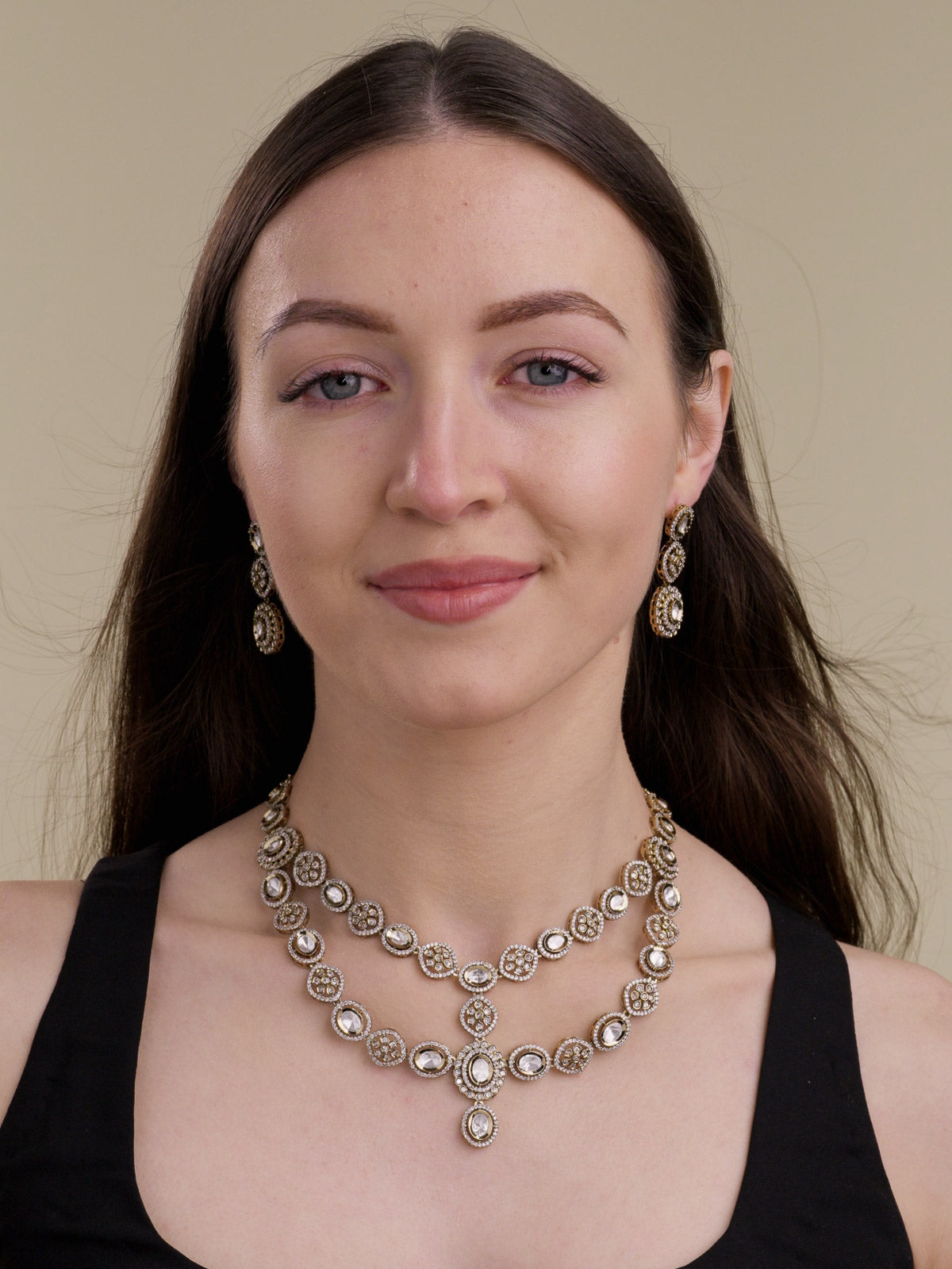 Model wearing a multilayer Kundan necklace set in Antique Gold Tone with neutral kundan-look stones, AD detailing, centre drop and matching earrings.