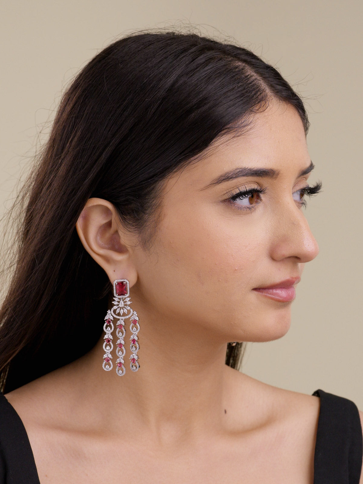 Model wearing a silver tone American Diamond earring with a Ruby Red square stud, clear CZ stones, curved centre accent, and three hanging teardrop strands in a side portrait shot.