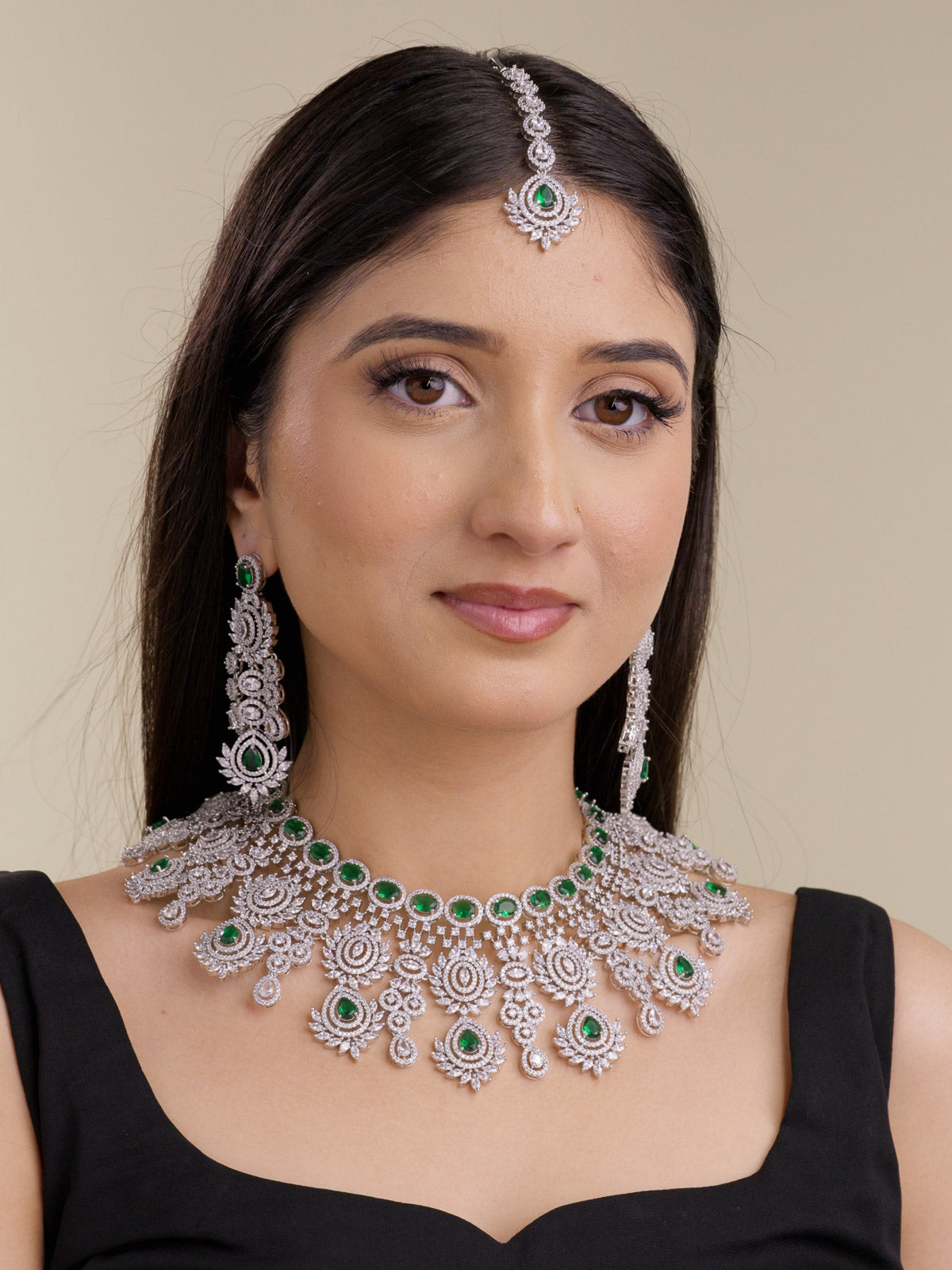 American Diamond necklace set in silver tone with rich green stones, shown on a model with matching long earrings and maang tikka in a full front bridal-style view.