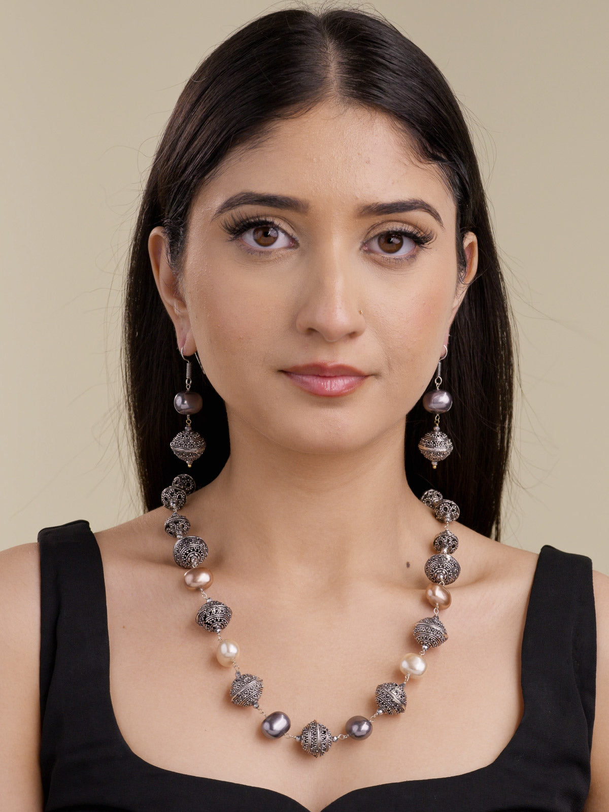 Beadwork necklace set in silver tone with textured metal beads, mixed grey, cream, and champagne pearl-style beads, and matching drop earrings on model front view