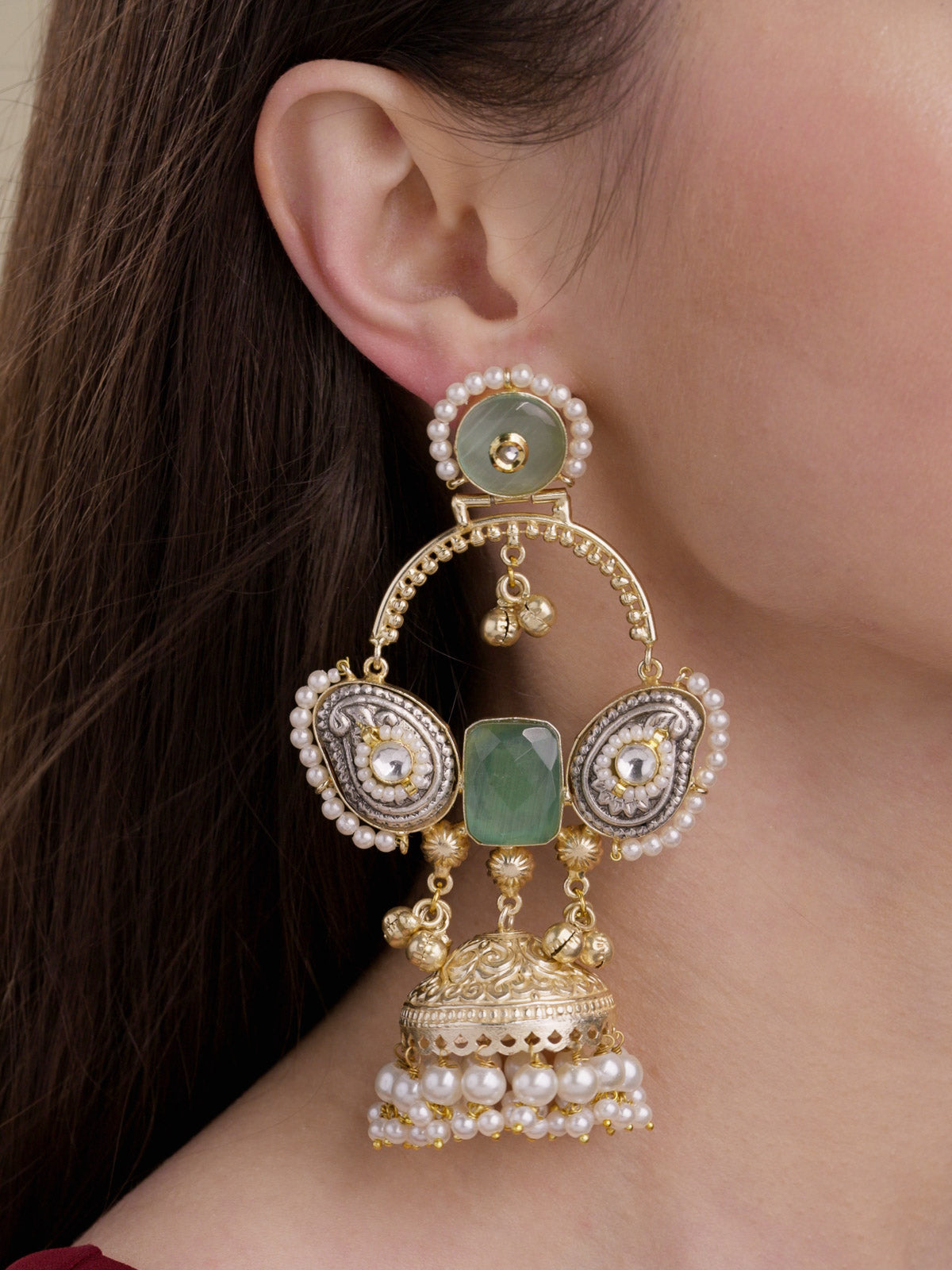 Model wearing fusion jhumka earrings in multi tone with mint stones, silver-tone paisley side panels, pearl borders, ghungroo drops and pearl-fringed jhumka dome, close-up model shot