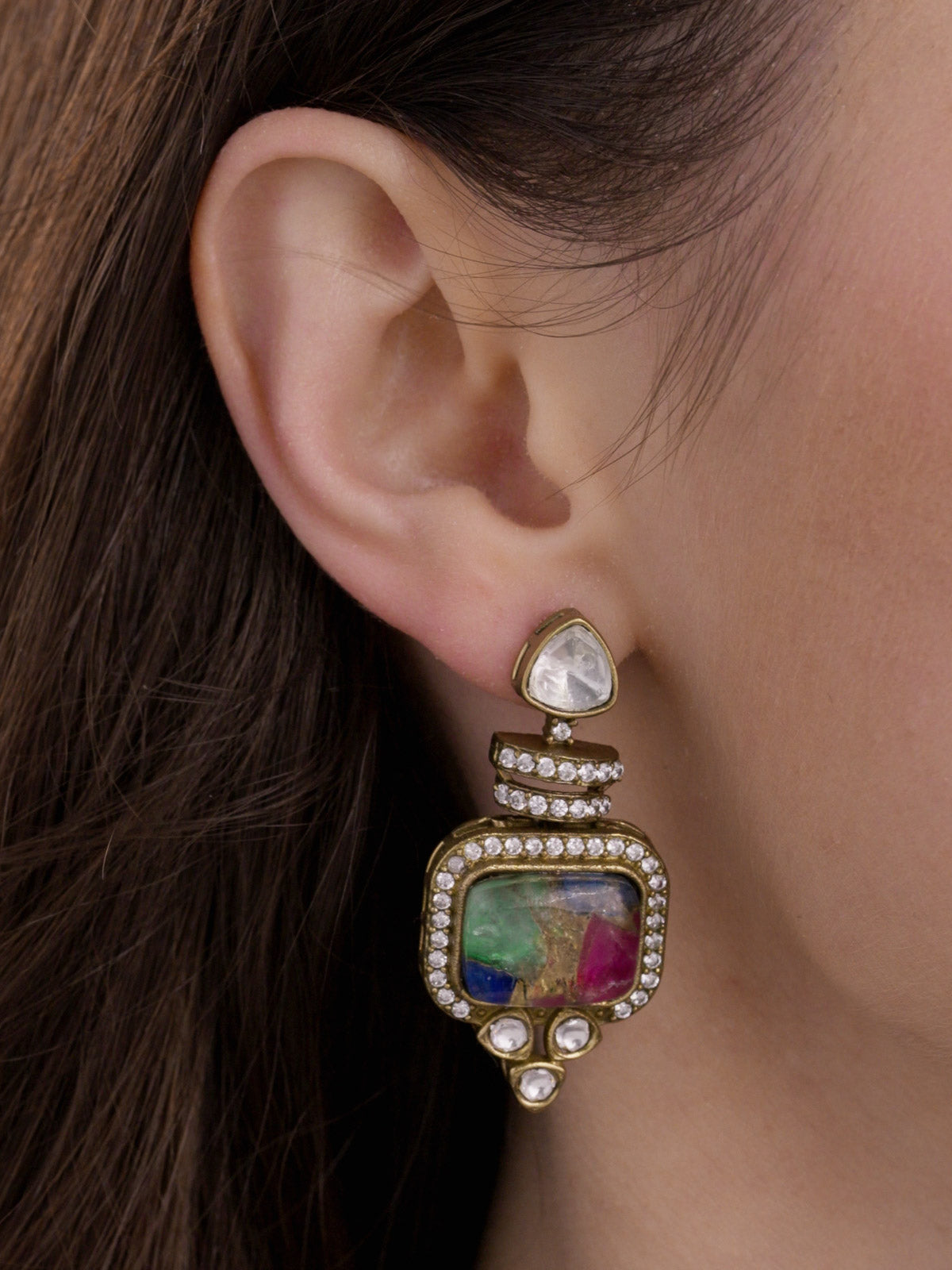 Close-up side view of a model wearing a matching Fusion drop earring in Antique Gold Tone with a textured multicolour centre stone, clear stone detailing, kundan-look accents, and part of the necklace visible.