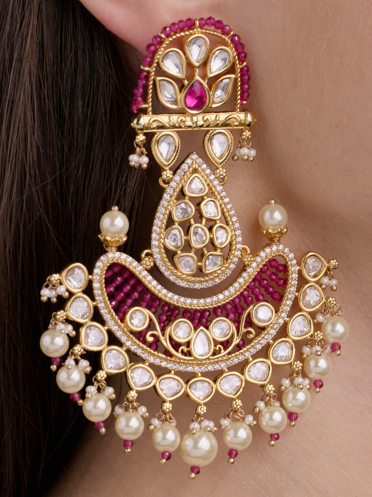 Close-up detail of a statement Kundan earring in Gold Tone with ruby red accents, kundan-look teardrop stones, American Diamond detailing, and pearl drops.
