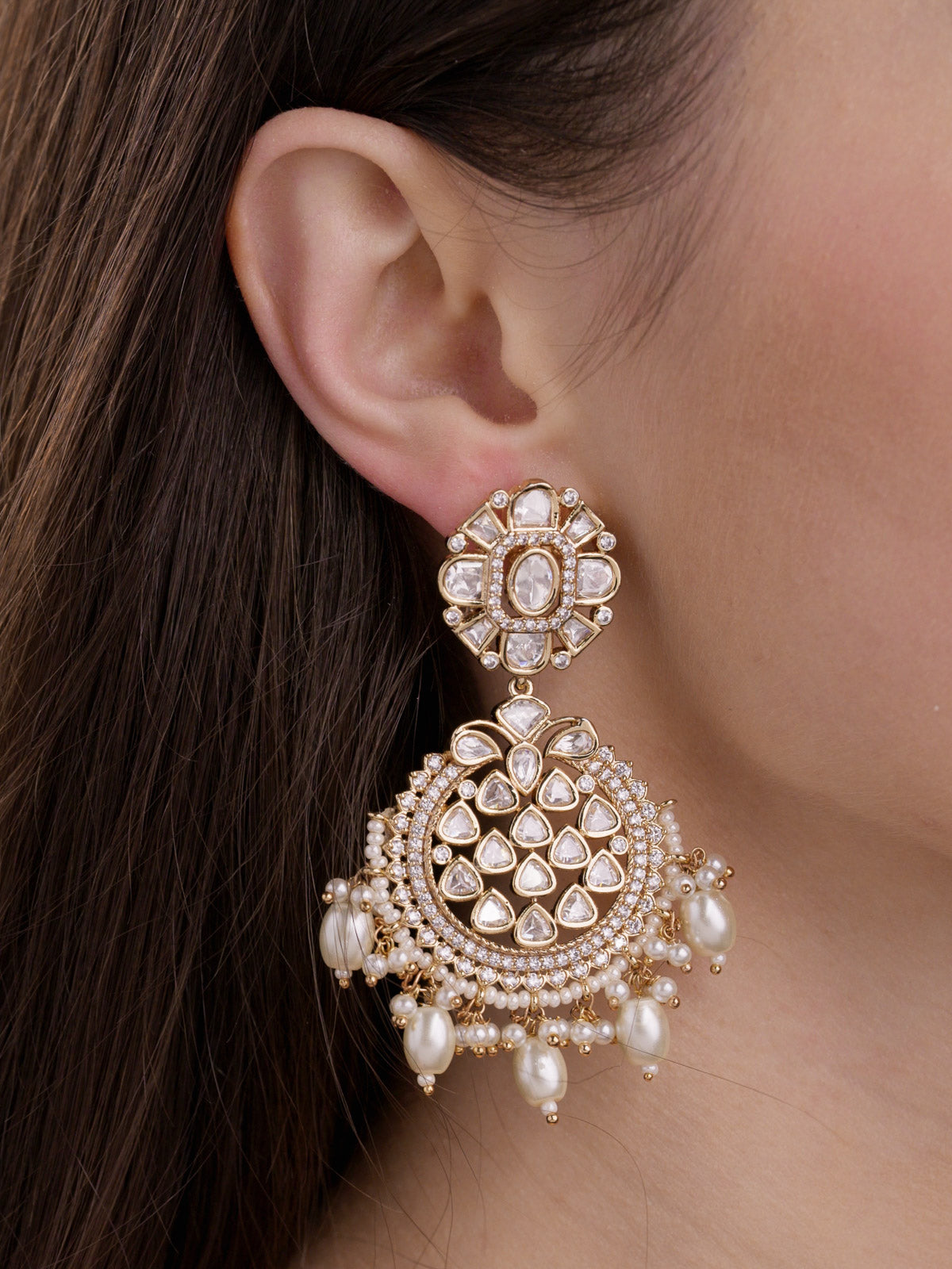 Close-up of a model wearing Champagne Gold Tone Kundan earrings with a round floral stud top, large rounded lower drop filled with teardrop kundan-look stones, CZ stone detailing, and pearl fringe drops.