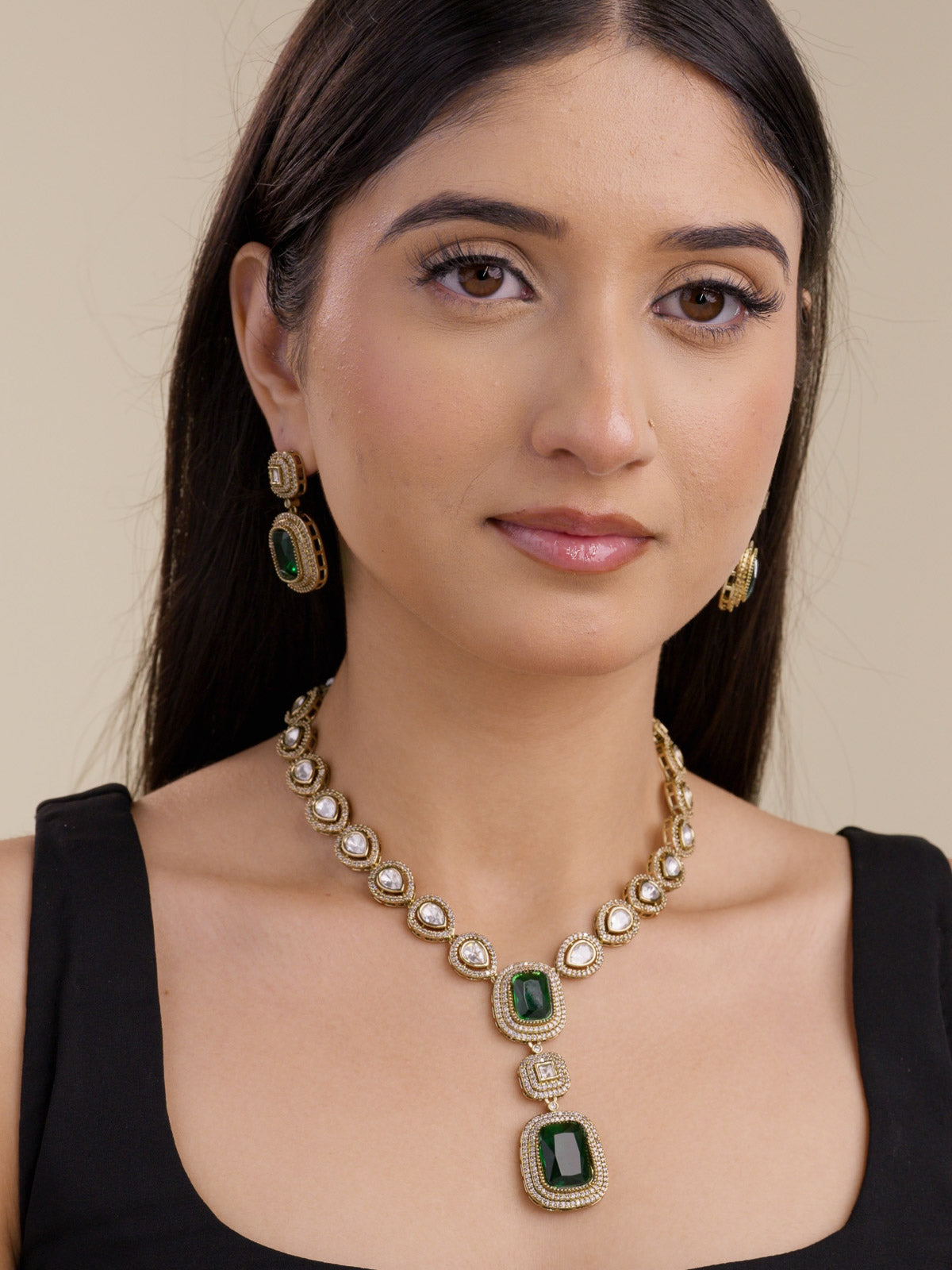 Kundan necklace set with emerald green rectangular centre stones and stepped double drop pendant, detailed with American Diamond stones in antique gold tone, with matching earrings, worn on model full look