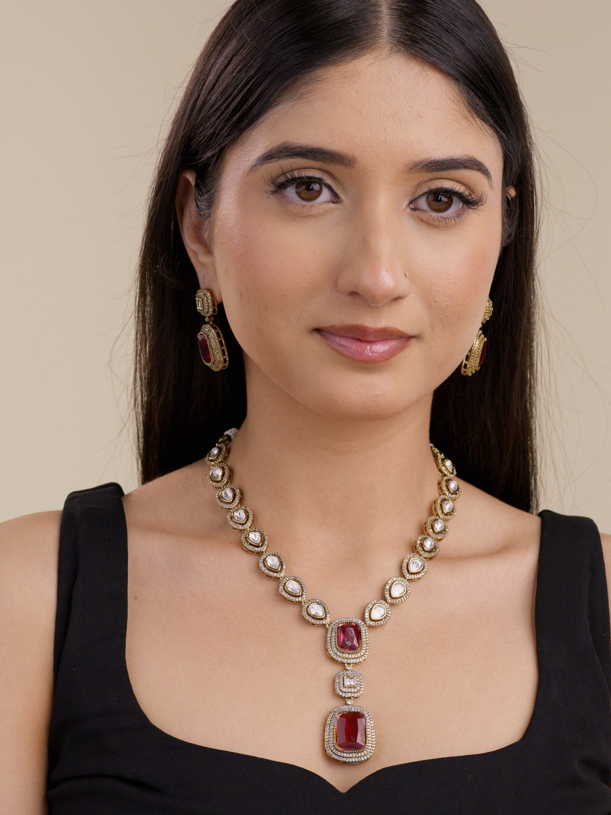 Kundan necklace set with ruby red rectangular centre stones and stepped double drop pendant, with American Diamond detailing in antique gold tone, with matching earrings, worn on model full look