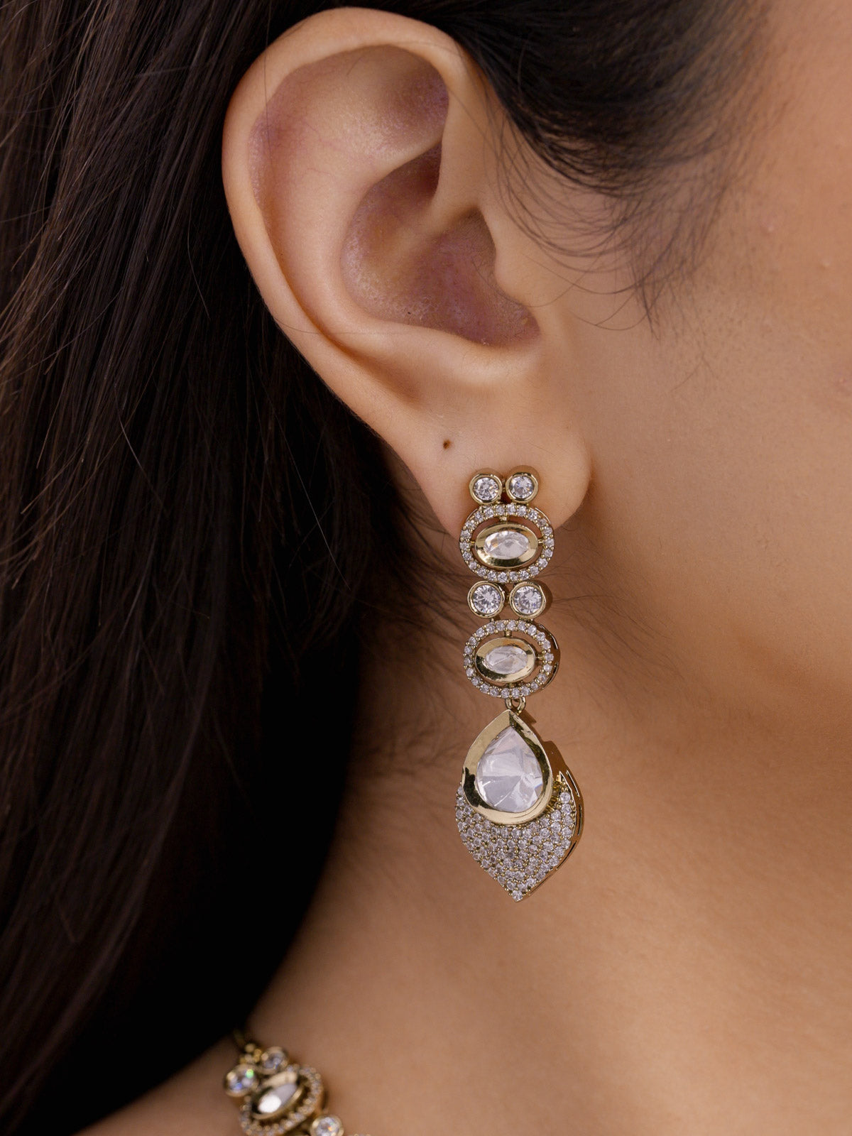 Kundan necklace set earrings with stacked oval kundan-look stones and American Diamond detailing in antique gold tone, long drop design with teardrop finish, close-up worn on model ear