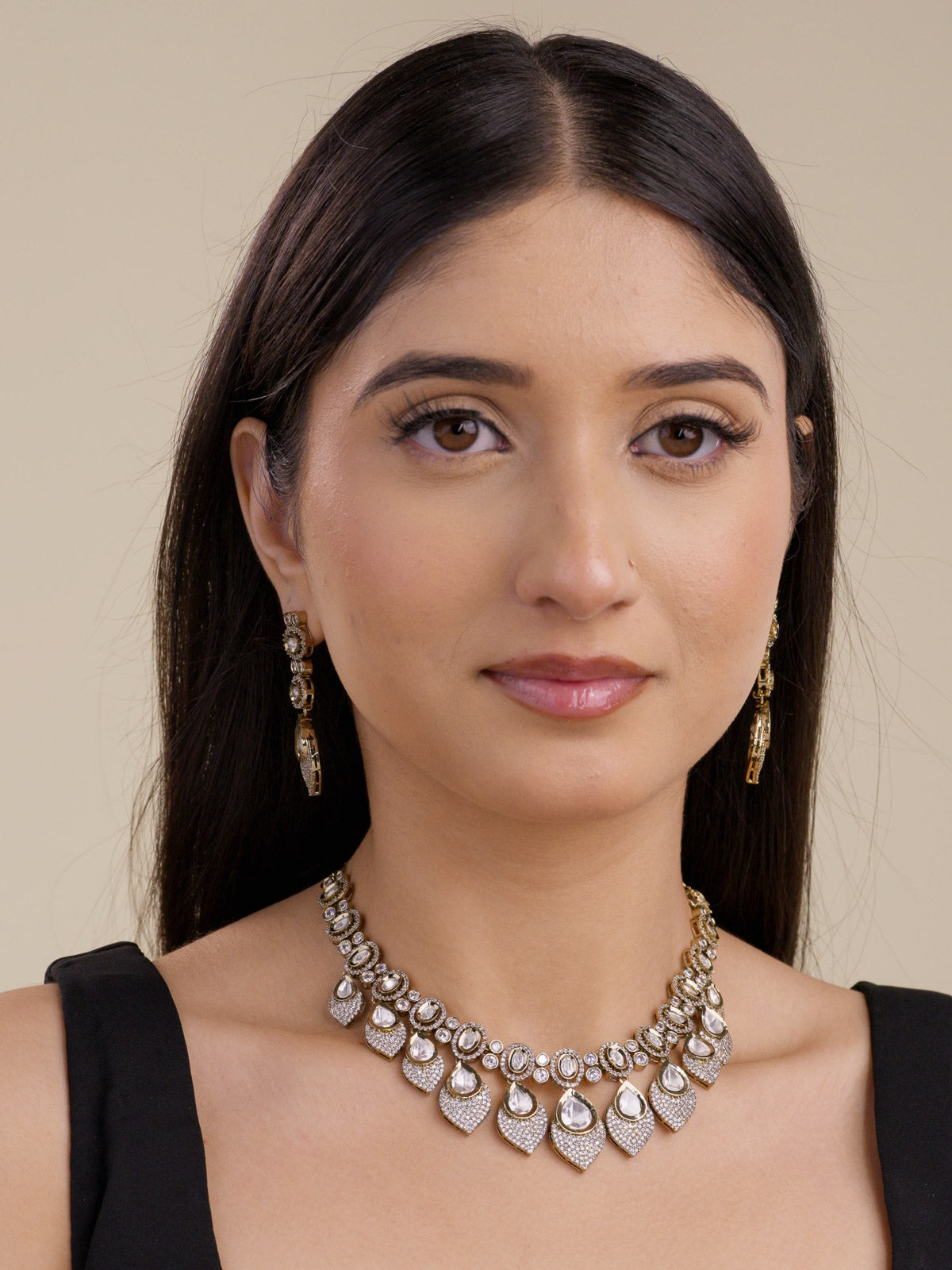 Kundan necklace set with oval kundan-look stones and petal-shaped drop design, with American Diamond detailing in antique gold tone, with matching drop earrings, worn on model full look
