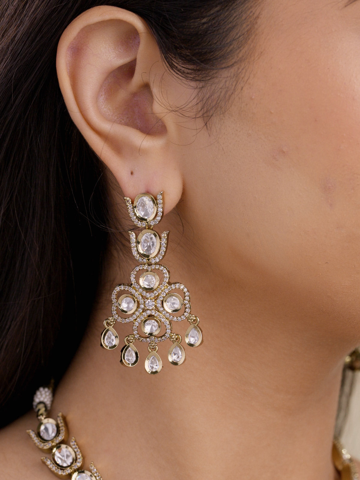 Kundan drop earrings with clustered centre and small hanging drops with american diamond detailing in antique gold tone on model