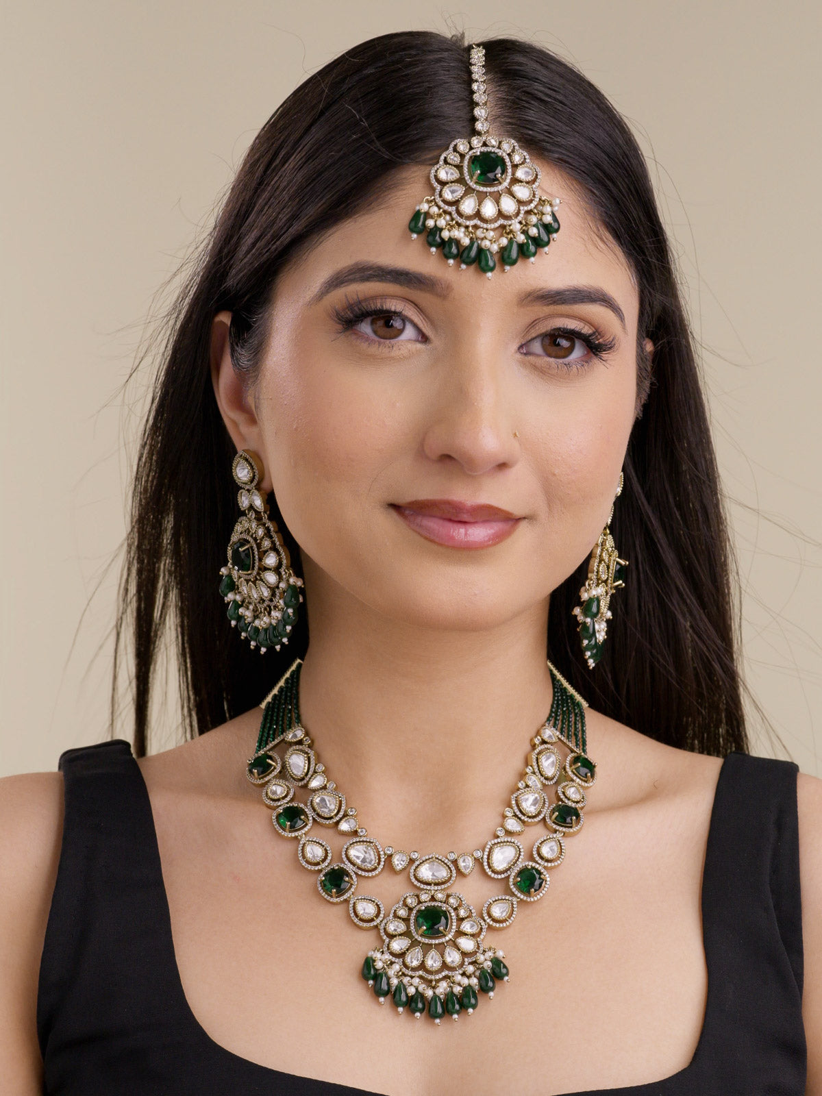 Kundan necklace set in antique gold tone with green stones, American Diamond outline detailing, matching earrings, maang tikka, and green bead drops on model