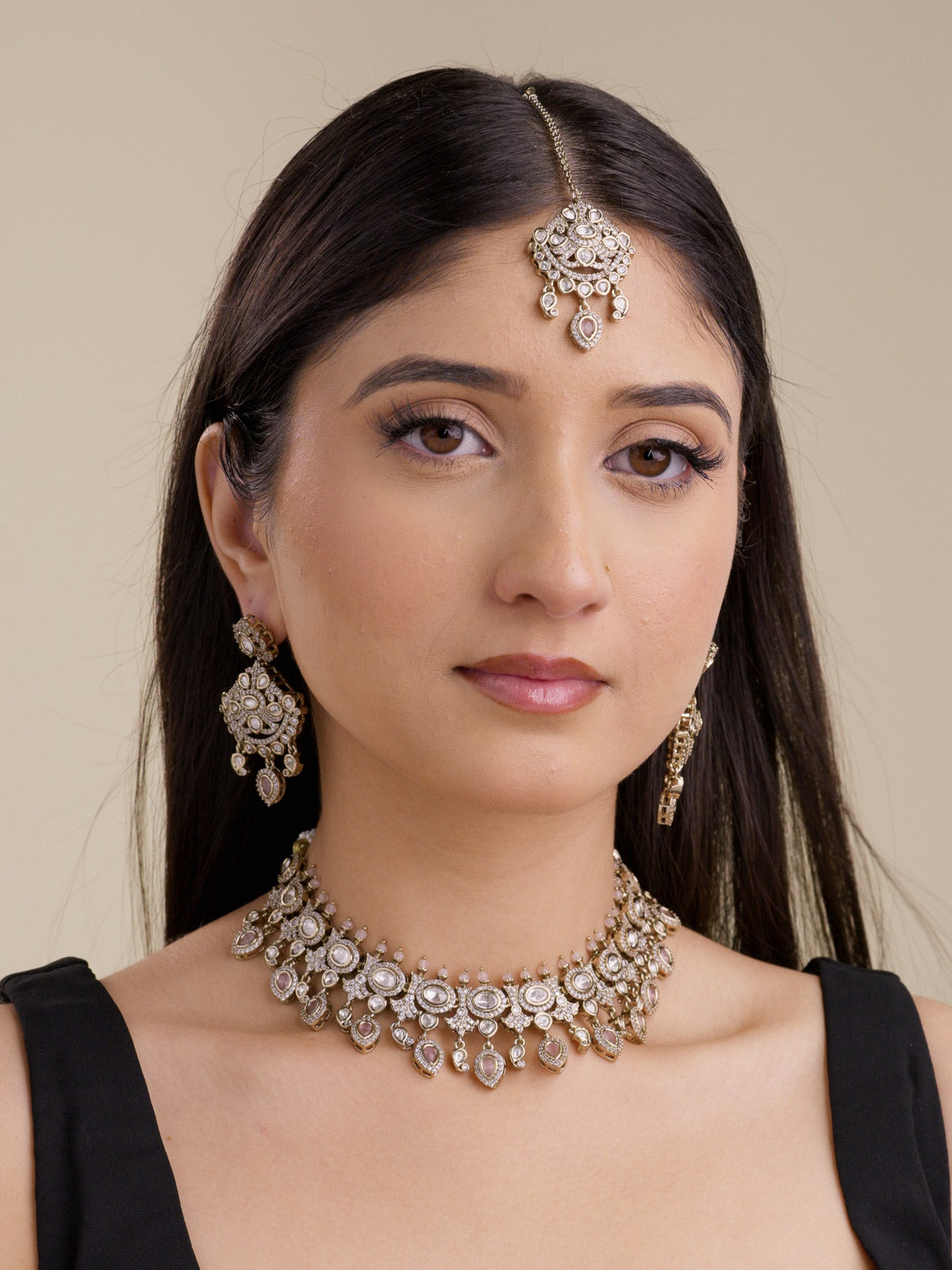 Front model view wearing a collar-style antique gold tone Kundan necklace set with pink stones, matching earrings, and maang tikka.