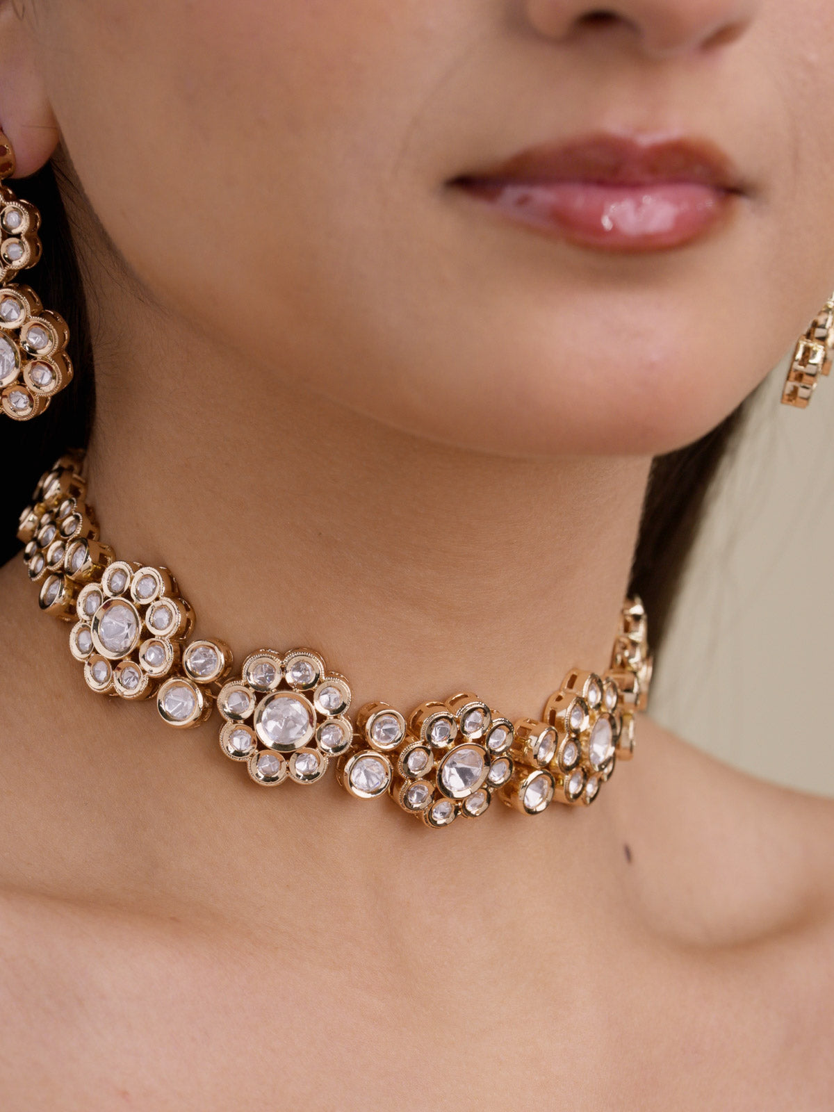 Close-up of model wearing a champagne gold tone Kundan choker necklace set with round floral kundan-look stone clusters and partially visible matching earrings.
