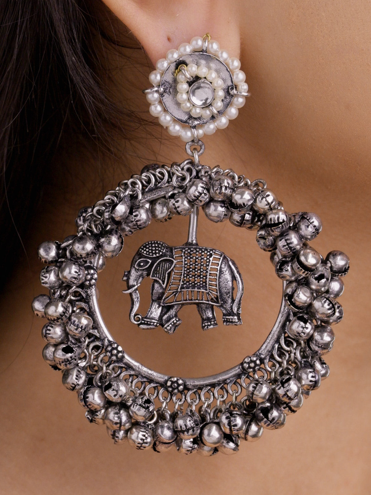 Extreme close-up of oxidised elephant hoop earring with pearl-style circular stud top, suspended elephant centre, and layered metal bead edging.