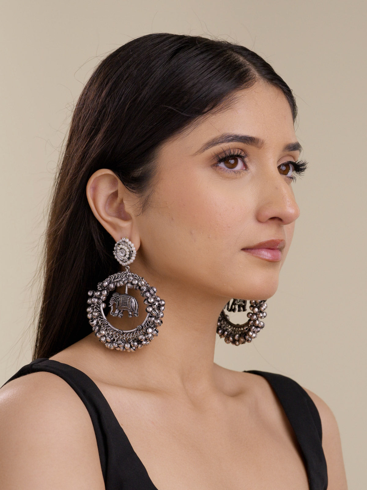 Model wearing oxidised elephant hoop earrings with pearl-style stud tops, round metal bead edging, and a neutral side portrait view.
