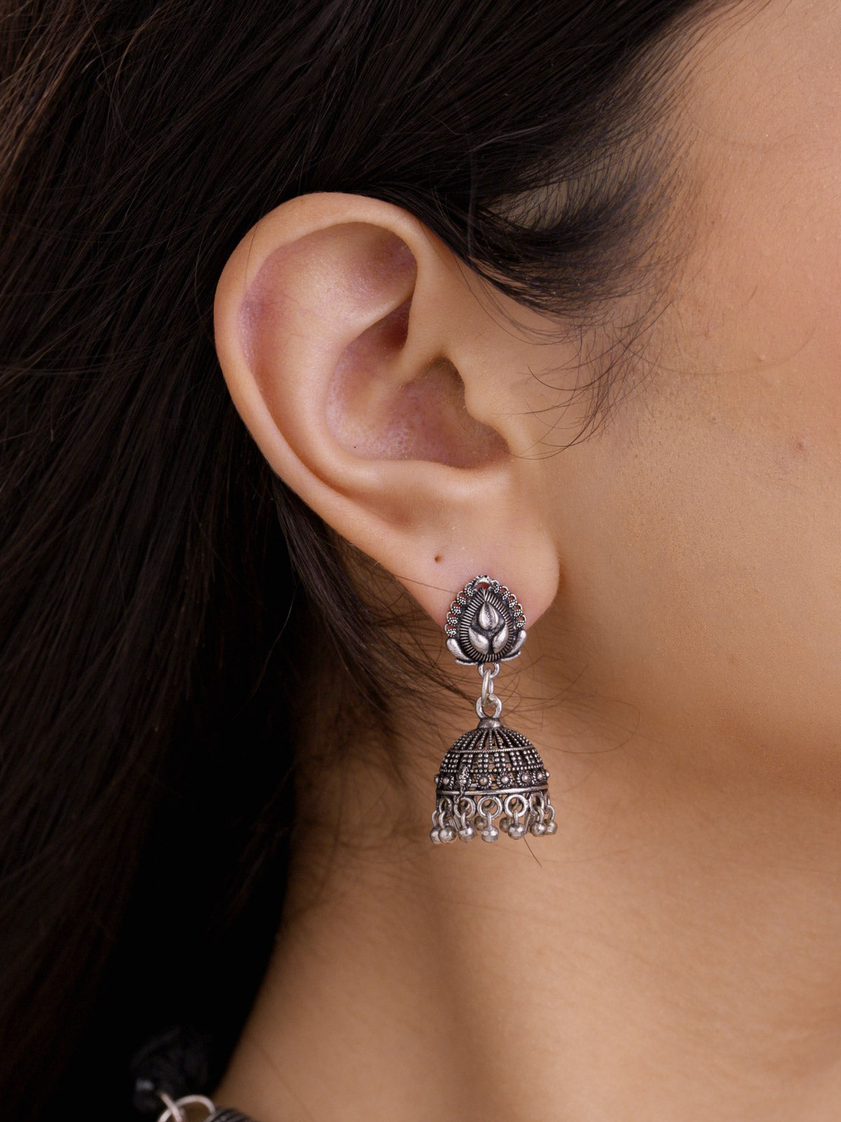 Oxidised jhumka earring with teardrop top detail and small dangling accents shown in a close model view.