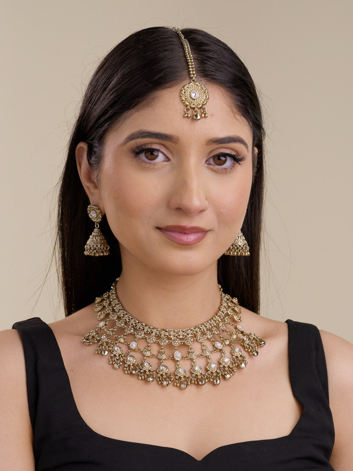 Rajwadi necklace set in antique gold tone with layered coin-style detailing, clear stone accents, matching jhumka earrings, and maang tikka shown on model.