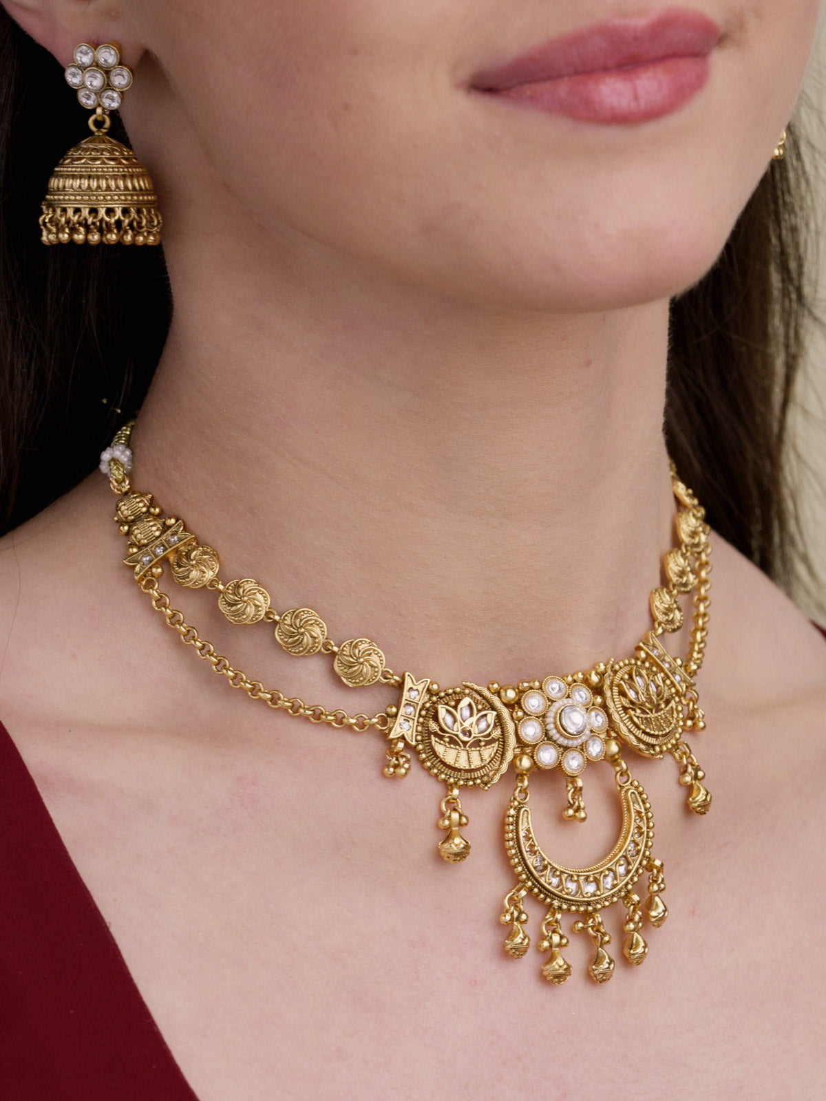Matte gold tone Rajwadi necklace set with round medallion links, clear stone centre, crescent lower pendant, small dangling metal drops, and matching jhumka earrings on model close-up.